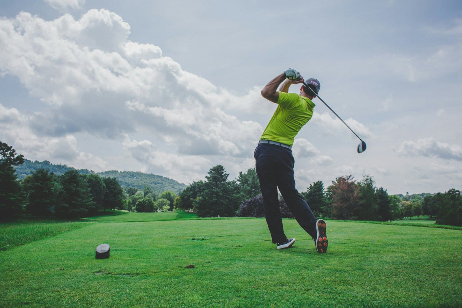 A golfer teeing off on a private club course on a clear day