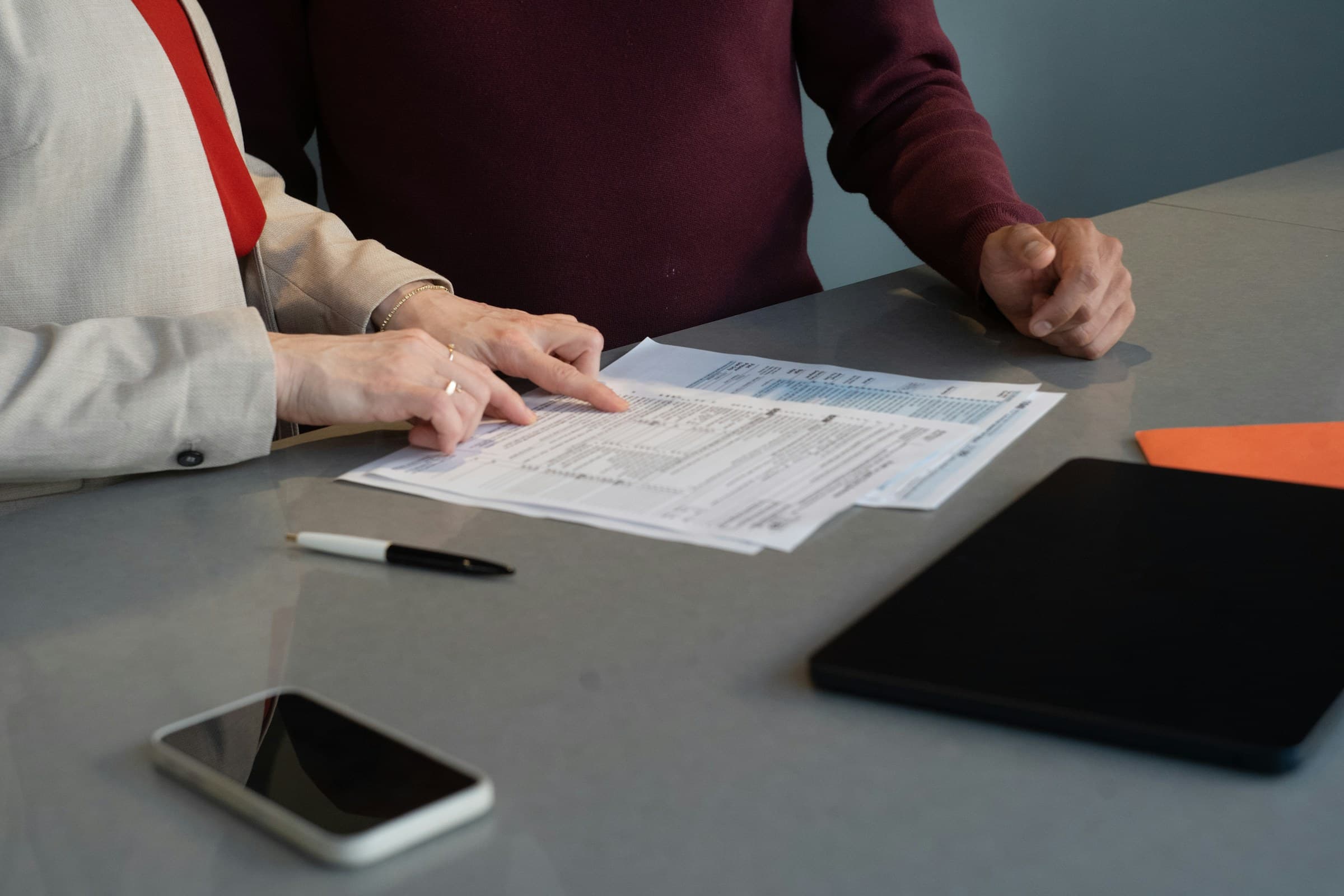 Two professionals reviewing paperwork together at a conference table